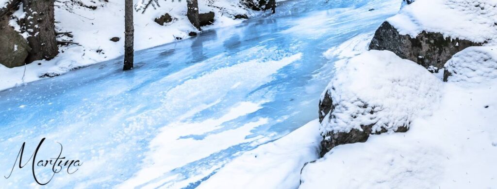 Frozen Maxwell Creek winding between snow-covered boulders and conifers