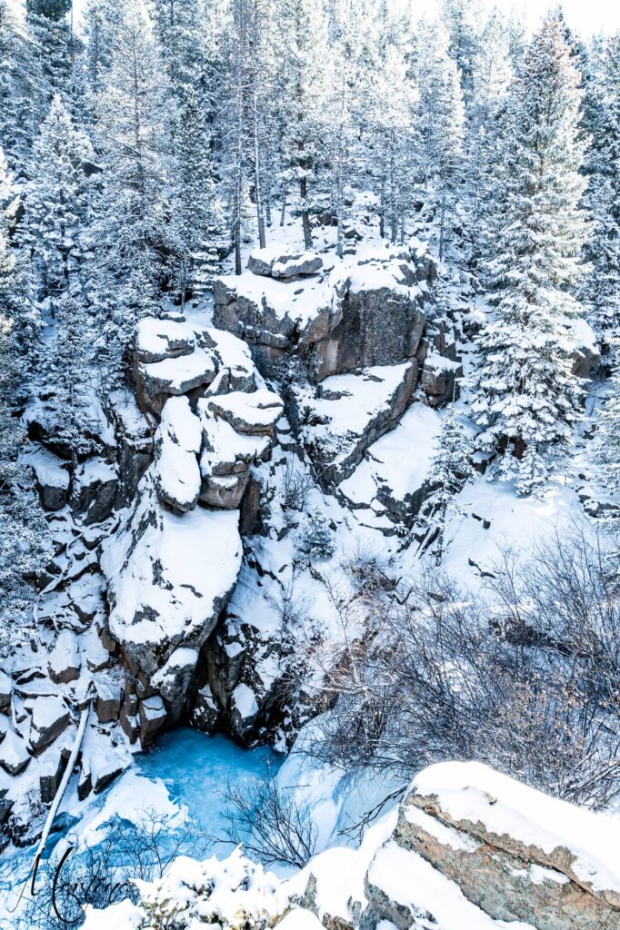 Maxwell Falls frozen in winter, snow-covered granite cliffs above a blue ice pool at the base