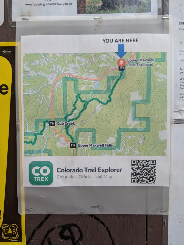 A COTREX trail map on the kiosk with a You Are Here arrow at the Lower Maxwell Falls Trailhead and a QR code for the Colorado Trail Explorer app.