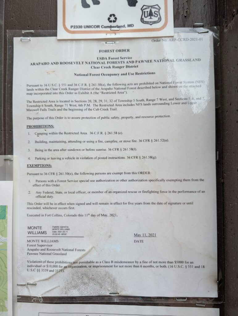 The Forest Service order ARP-CCRD-2021-01 posted behind plastic on a trailhead kiosk.