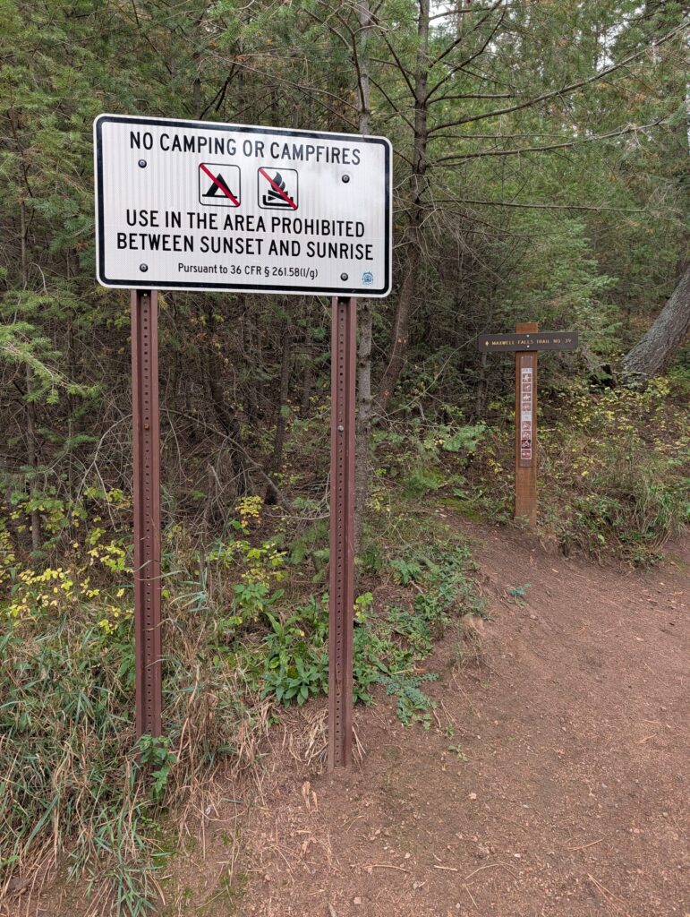 A white Forest Service sign reading No Camping or Campfires, Use in the area prohibited between sunset and sunrise.